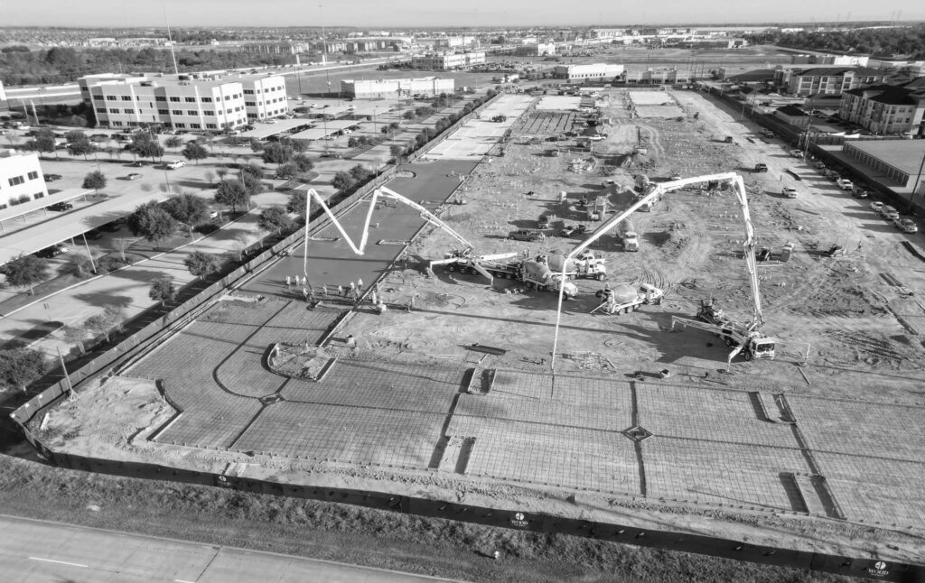 Aerial view of an Aggtech Concrete Construction crew placing a large commercial concrete foundation with two boom pumps
